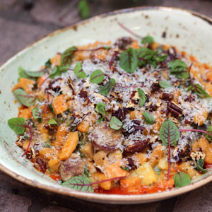 dish of gnocchi in red sauce topped with micro green