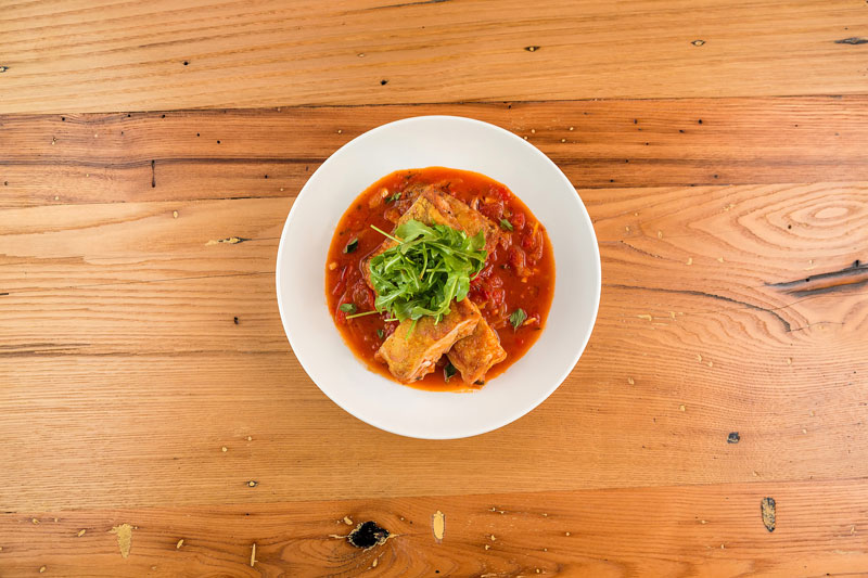 overhead view of fried ravioli in red sauce topped with greens